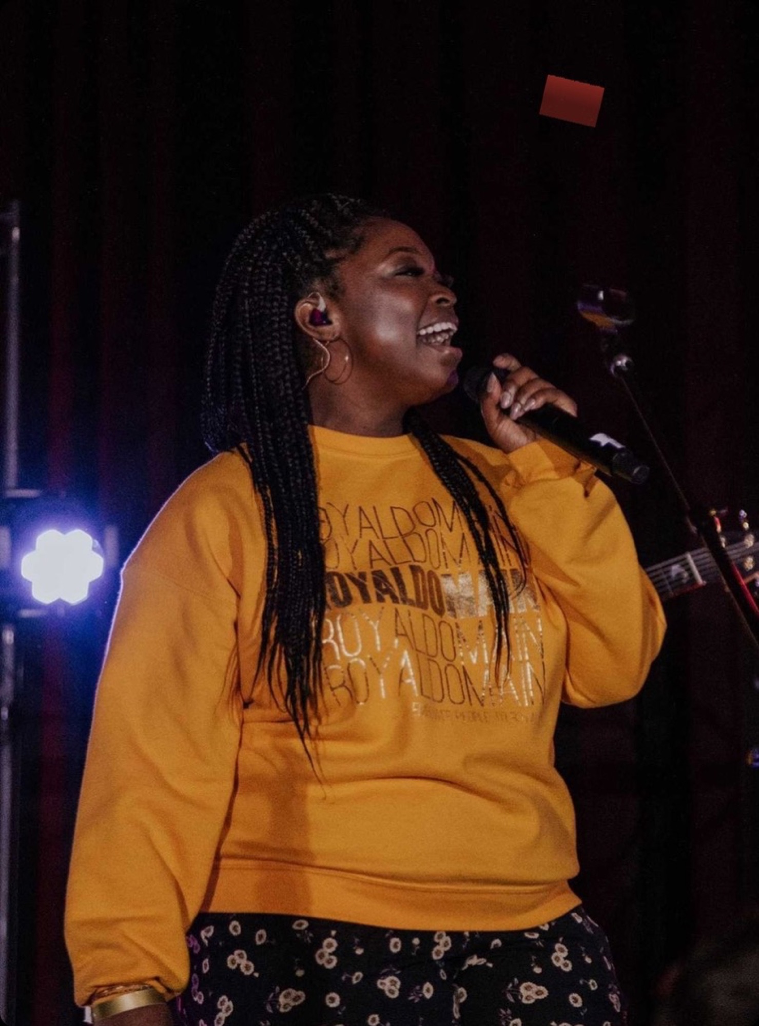 Lou Taylor laughing mid-song in a gold sweatshirt